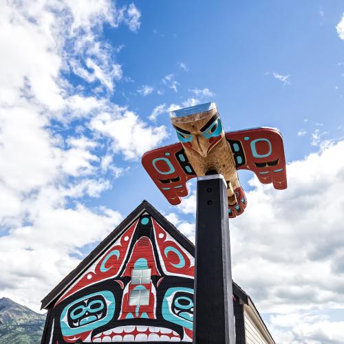 A Carcross/Tagish First Nation totem pole and mural on a small building