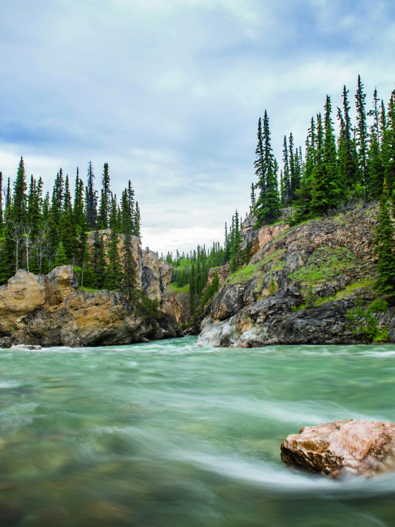 A teal river runs towards a canyon